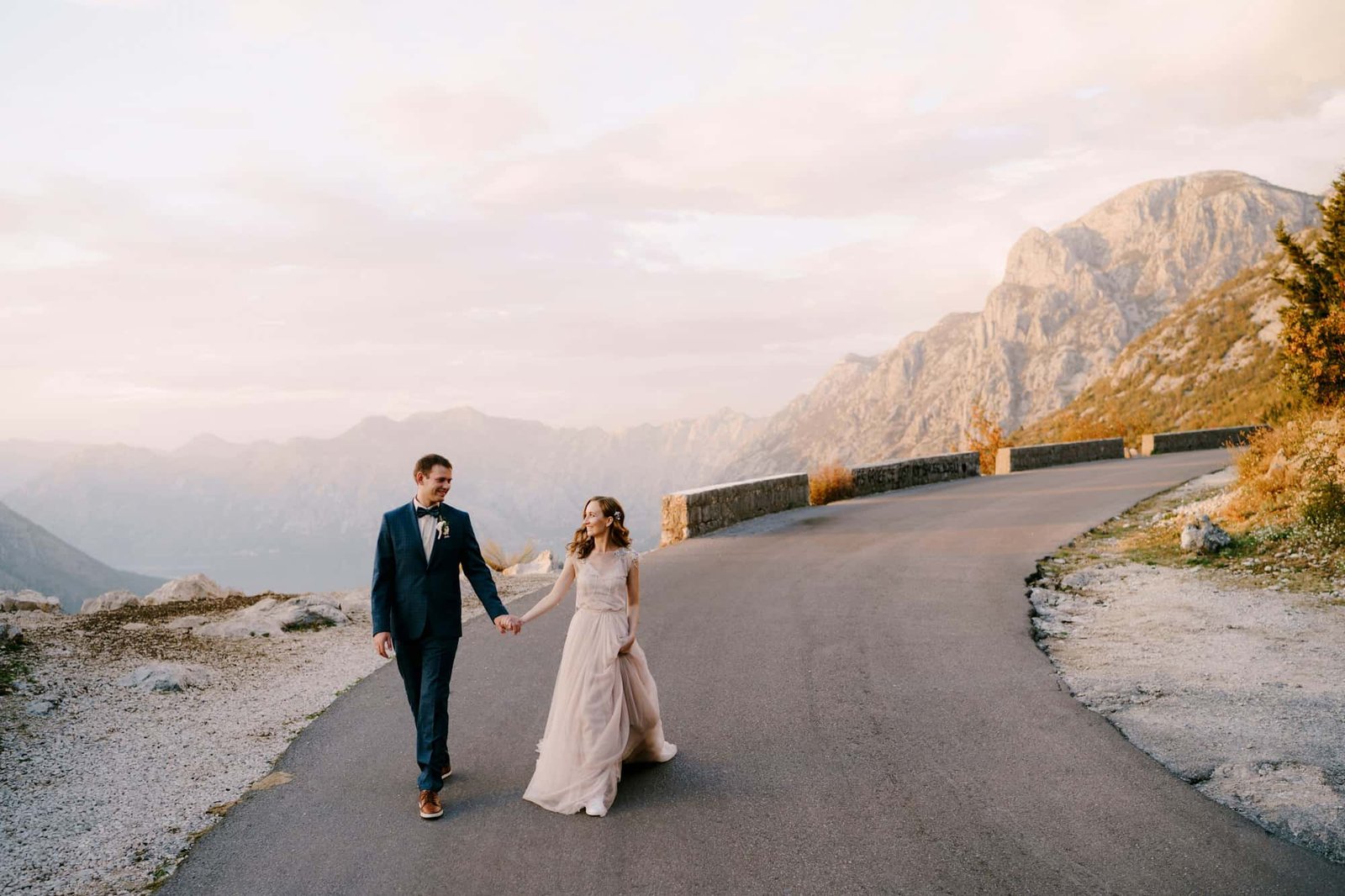 bride-and-groom-are-walking-along-the-asphalt-road-against-the-background-of-mountains.jpg
